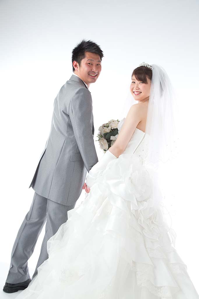 純白のウェディングドレスを着た新婦とタキシードを着た新郎